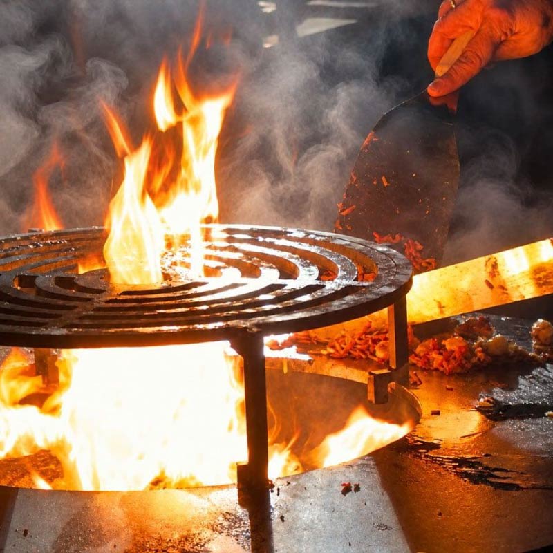 LOriental chef cooking on open flame grill on Mongolian Fire  Grill live station